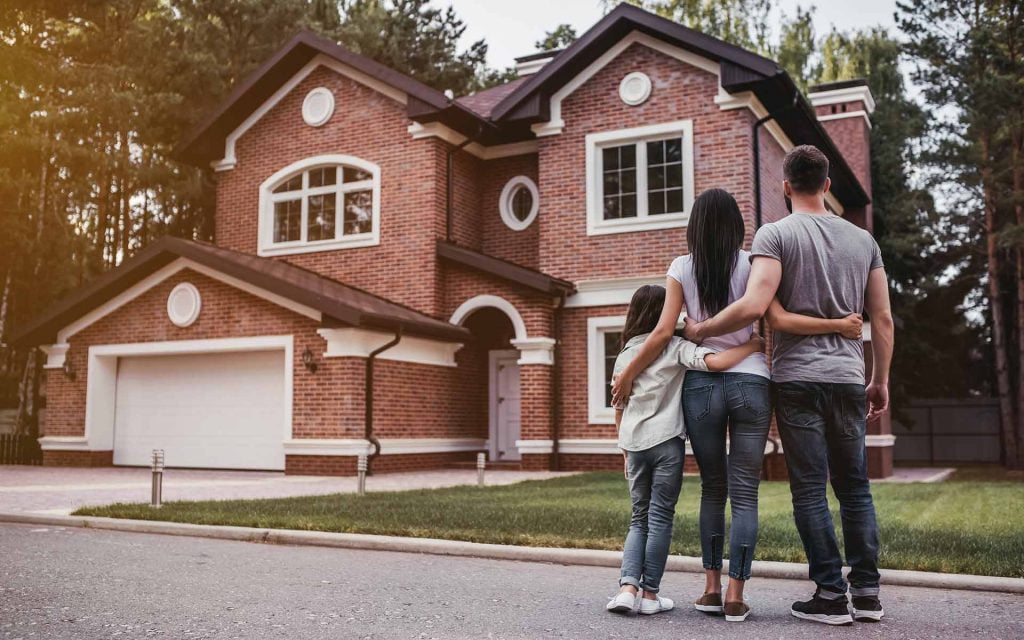happy family standing in front of new brick home